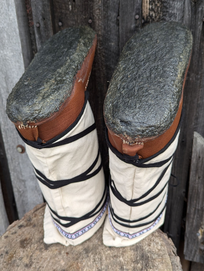 Pair of vintage boots with white soles and brown tops on a wooden surface.